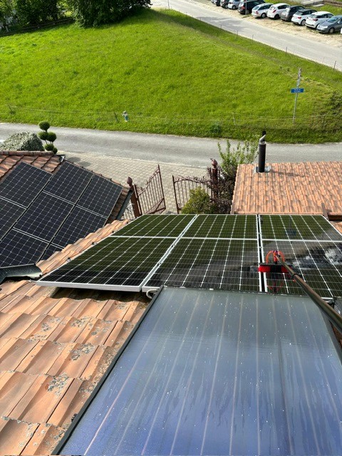 a man in a blue shirt is washing a driveway